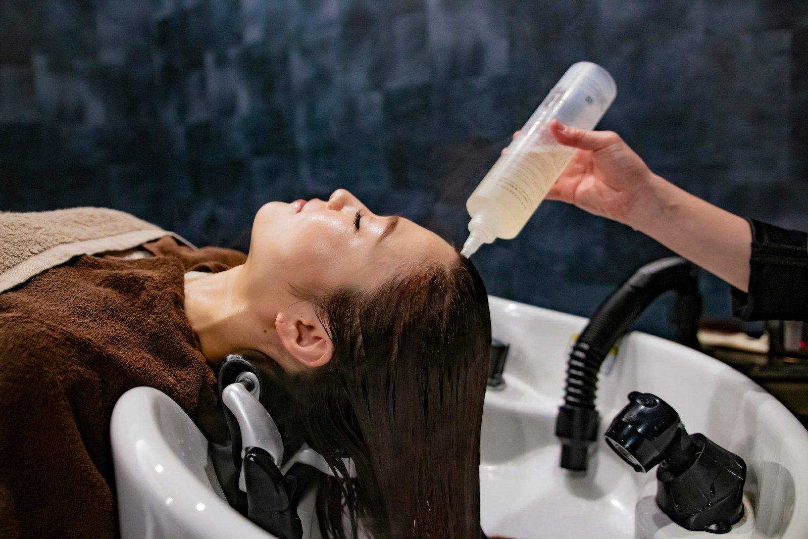Nourishing serum poured along the parting during a head spa