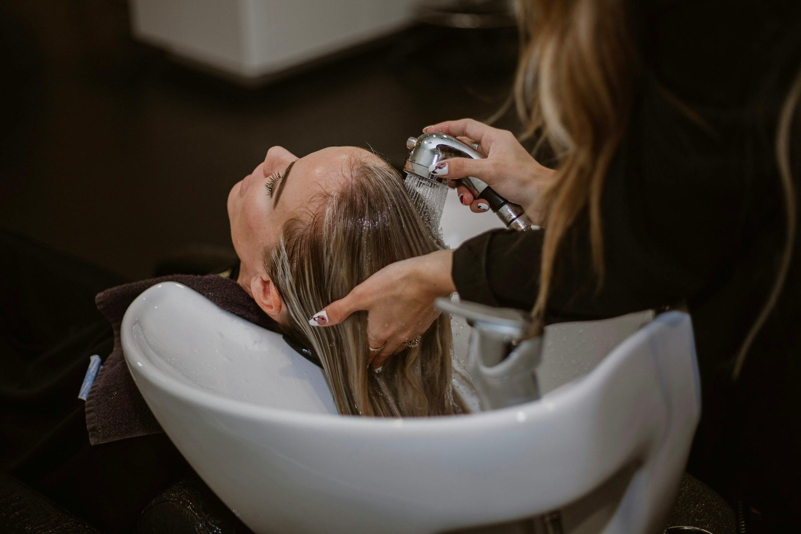Client relaxing during a hair wash at the salon basin